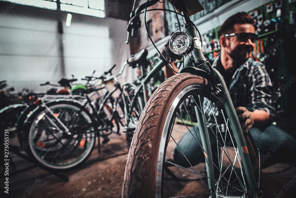 Handsome dilligent male in sunglasses is fixing tyres for busy customer. Handsome dilligent male in sunglasses is fixing tyres for busy customer.