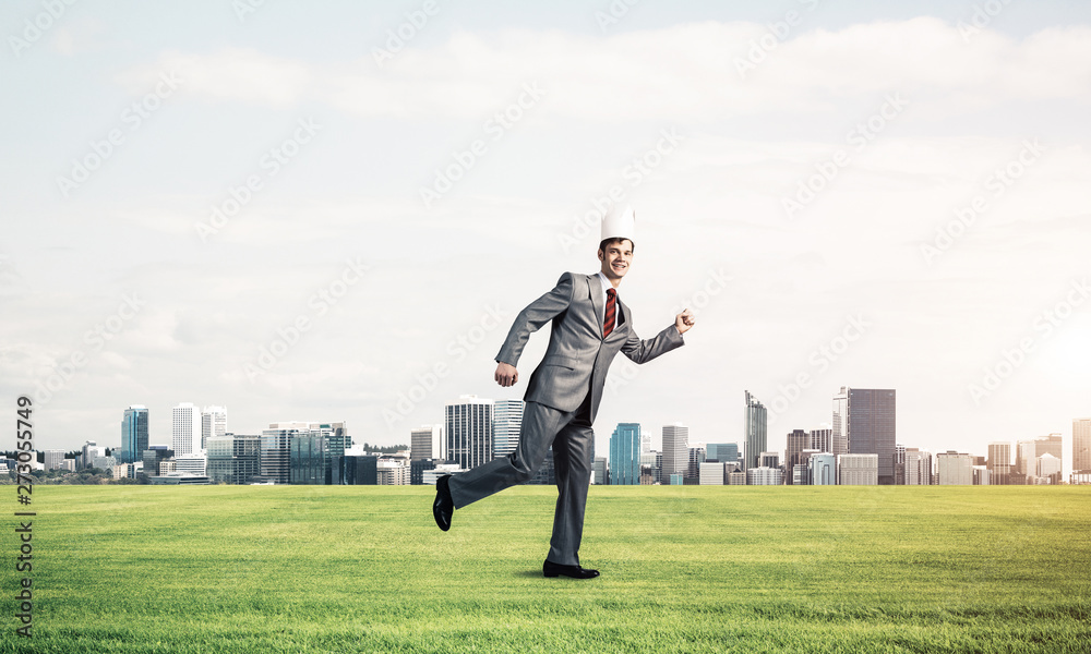 King businessman in elegant suit running on green grass and modern cityscape at background King businessman in elegant suit running on green grass and modern cityscape at background