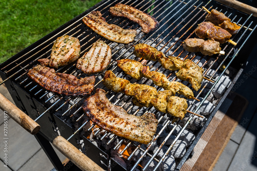Different types of meat fried on the home grill, standing on a home garden on the paving stone.