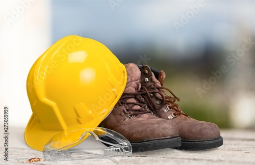 Safety helmet with earphones and goggles on construction background