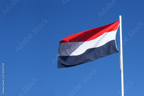Dutch flag waving in the wind at a sunny day with a clear blue sky