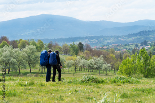 A couple is traveling with backpacks across the field © Formatoriginal