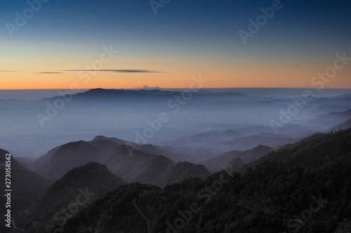 Mountain view misty morning of top hills around with sea of fog with red and yellow sun light in the sky background, sunrise at Doi Ang Khang, Monzone view point, Chiang Mai, Thailand. © Yuttana Joe