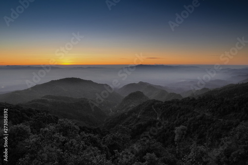 Mountain view misty morning of top hills around with sea of fog with red and yellow sun light in the sky background, sunrise at Doi Ang Khang, Monzone view point, Chiang Mai, Thailand.