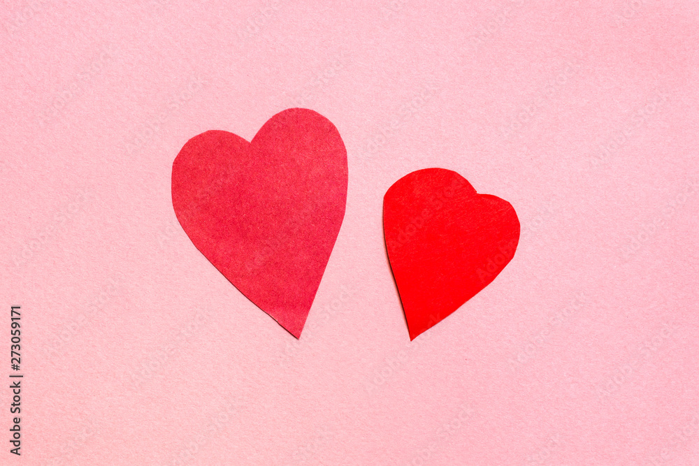 two hearts cut from red paper on pink paper