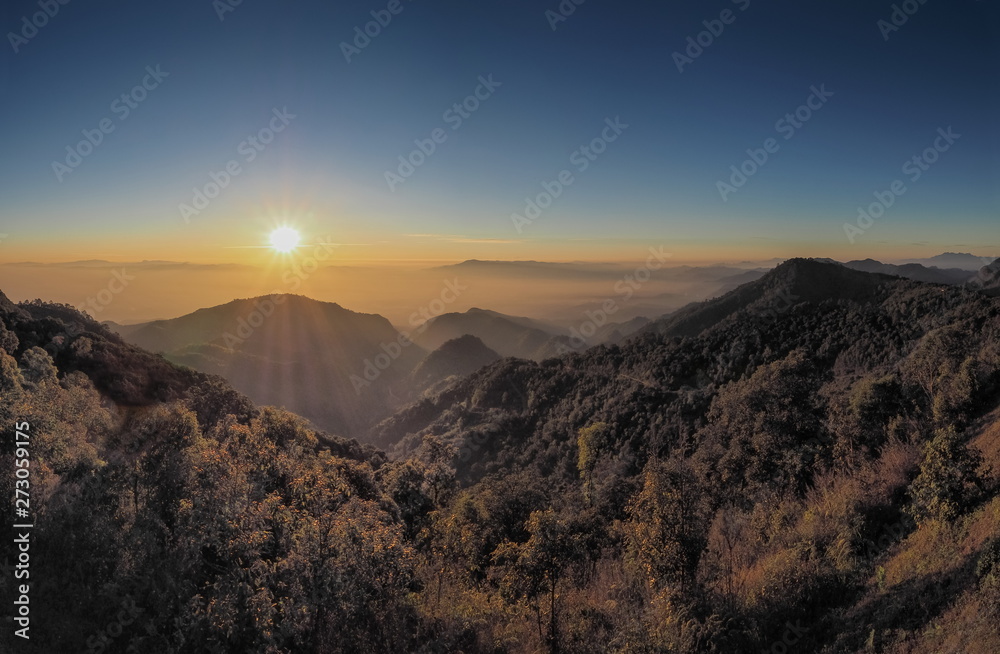 Mountain view misty morning of top hills with yellow sun light in the sky background, sunrise at Doi Ang Khang, Monzone view point, Chiang Mai, Thailand.