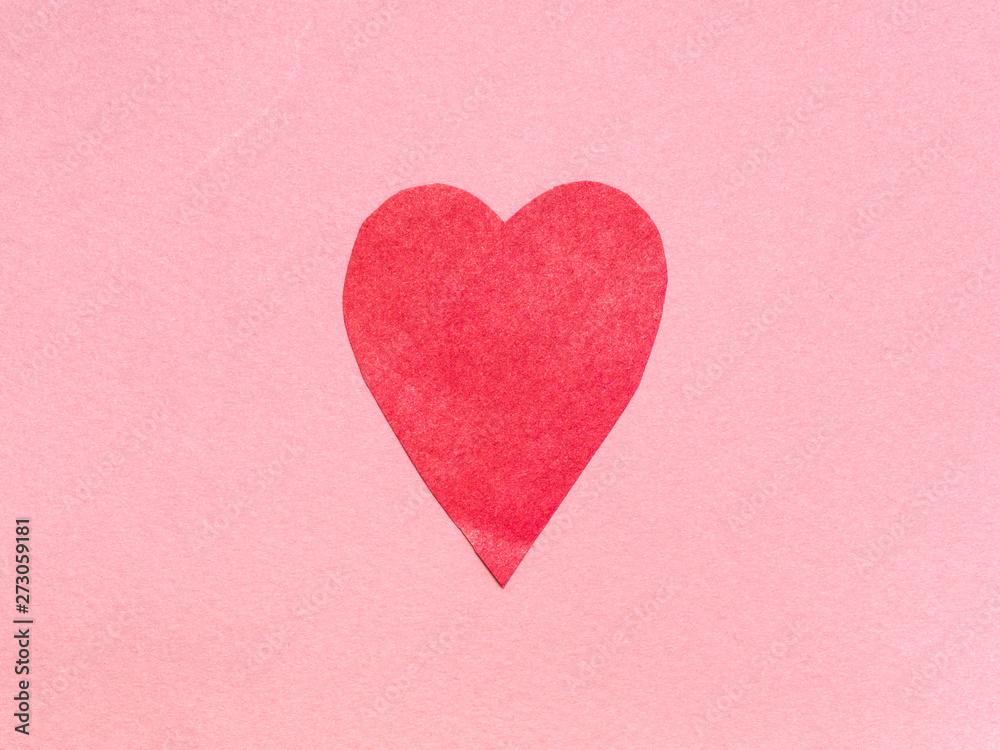 one heart cut from red paper on pink paper
