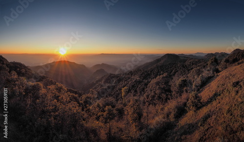 Mountain view misty morning of top hills with yellow sun light in the sky background, sunrise at Doi Ang Khang, Monzone view point, Chiang Mai, Thailand.