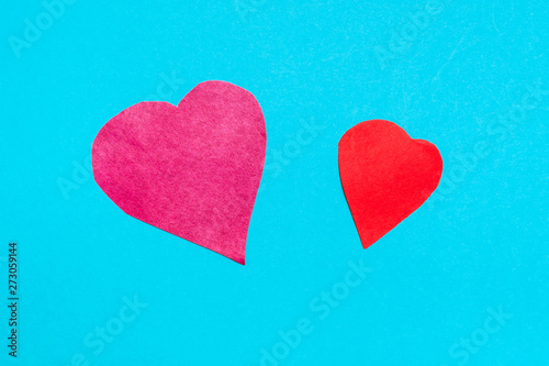 two hearts cut from red papers on blue paper