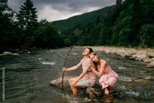 Fototapeta Naklejka Na Ścianę i Meble -  Lifestyle loving couple hugging at stone in the river.
