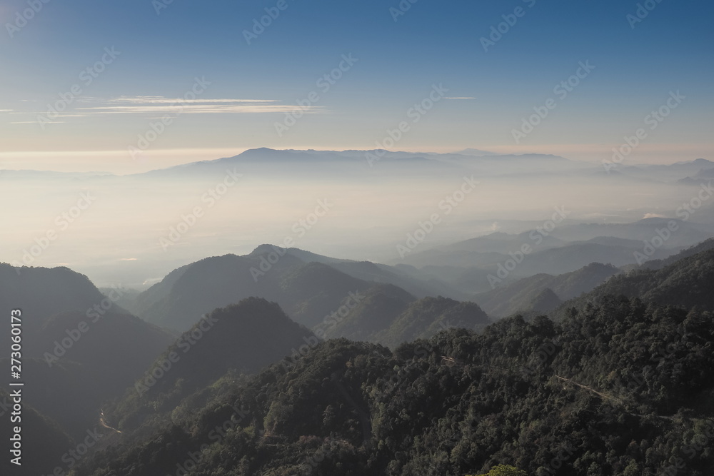 Mountain view misty morning of top hill around with sea of mist and blue sky background, sunrise at Doi Ang Khang, Monzone view point, Chiang Mai, Thailand.