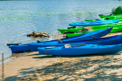 Fototapeta Naklejka Na Ścianę i Meble -  A lot of kayaks are on the river bank. Empty kayaks on the shore of the bay