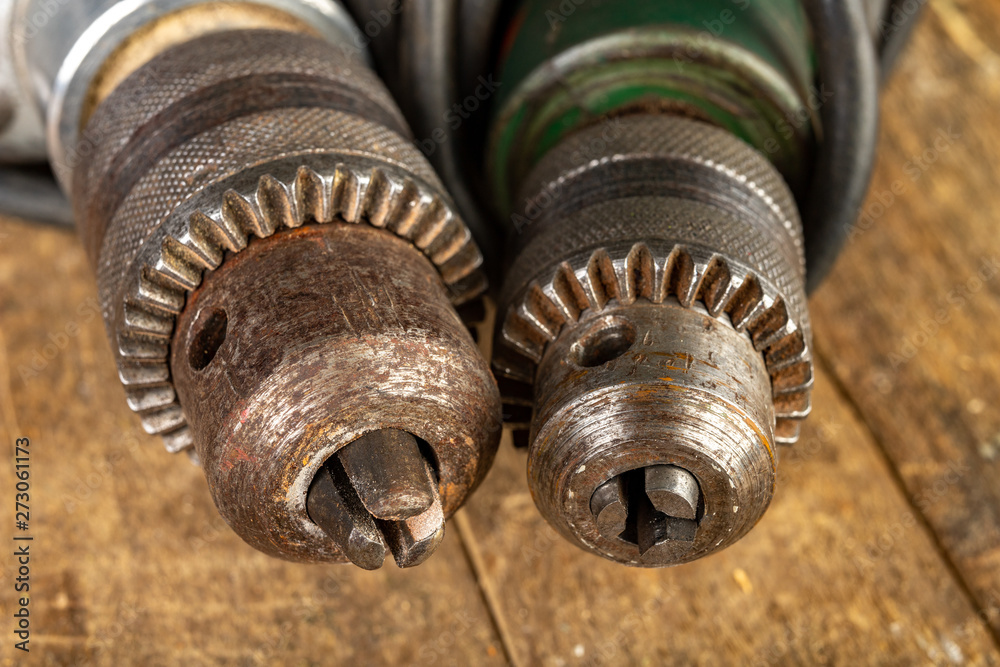 Old drills on a wooden workshop table. Rusty drill holder in an old drill. Old drills on a wooden workshop table. Rusty drill holder in an old drill.
