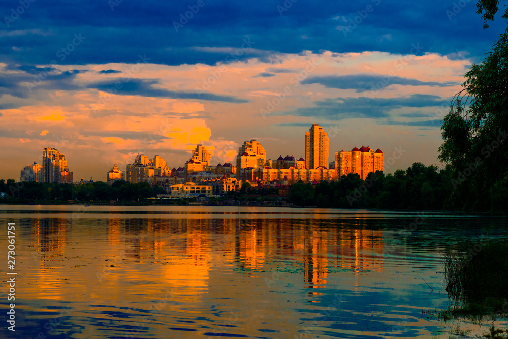 Naklejka premium Cityscape at sunset with a lake in the foreground