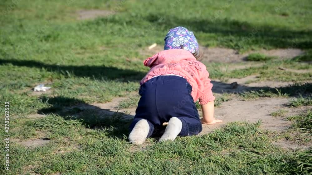 Smiling cute playful little girl is standing on green grass. girl toddler walks around the lake learns to walk. sunny sping or summer day Smiling cute playful little girl is standing on green grass. girl toddler walks around the lake learns to walk. sunny sping or summer day