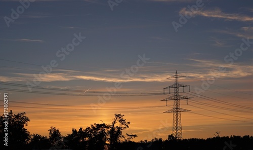 silhouette of a high voltage transmission tower at sunset, electricity pylon, power pole at sundown