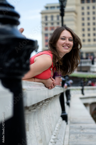 Stylish beautiful young woman in pretty dress posing on balcony.