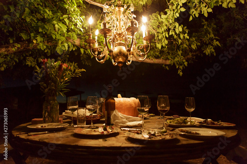 Outdoor dining table with rustic decor and chandelier
