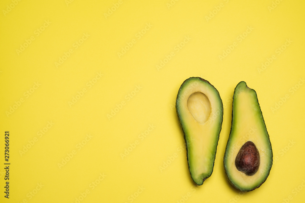 Cut in half avocado isolated on yellow background. Top view. Copy space. Creative concept