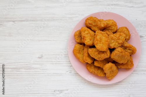 Chicken nuggets on a pink plate on a white wooden background, top view. Overhead, from above, flat lay. Copy space.