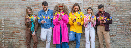 Group of diverse friends using social media on their mobile phones, with emoticons popping up from the screen, illustrating modern communication and connection photo