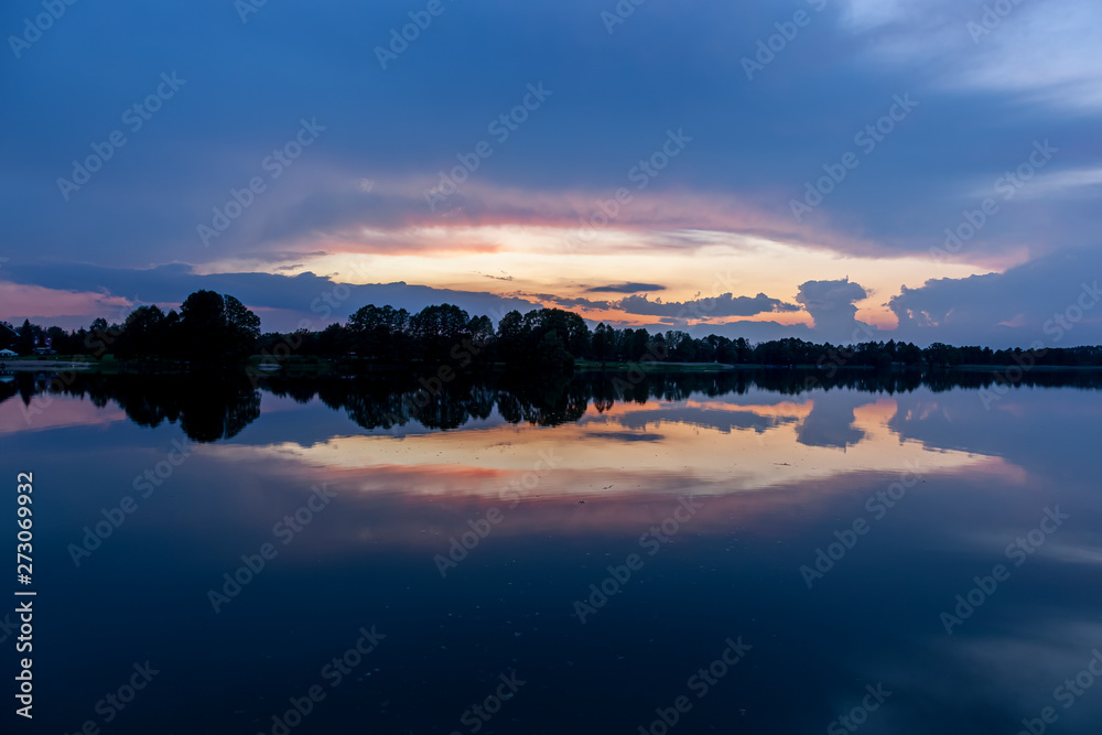 Zachód słońca nad jeziorem Kalwa w Polsce. Odbicie nieba w wodzie.