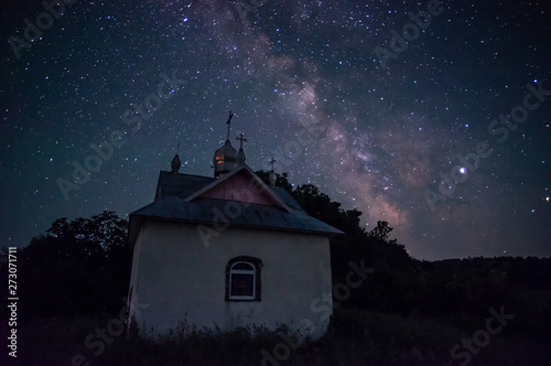 Little chapel in the forest against the background of the night starry sky