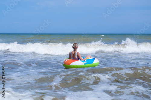 Girl teenager on an inflatable circle in the sea, ocean. Swim during the waves. © Konstiantyn Zapylaie