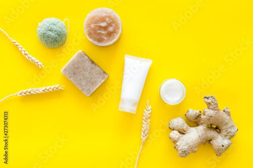 Natural herbal cosmetics with ginger and wheat on yellow background top view photo