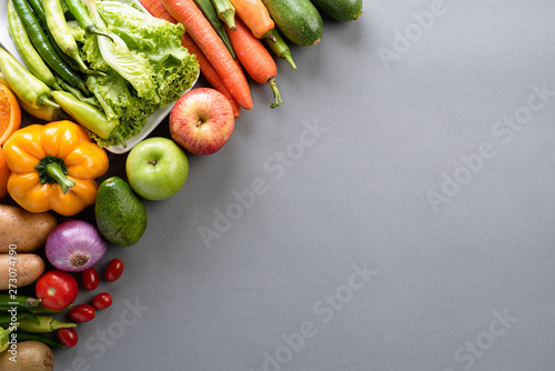 Healthy lifestyle and food concept. Top view of fresh vegetables, fruit, herbs and spices with a empty pink pastel plate on gray background.