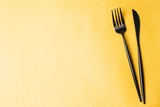 Fork, knife and linen napkin on yellow background