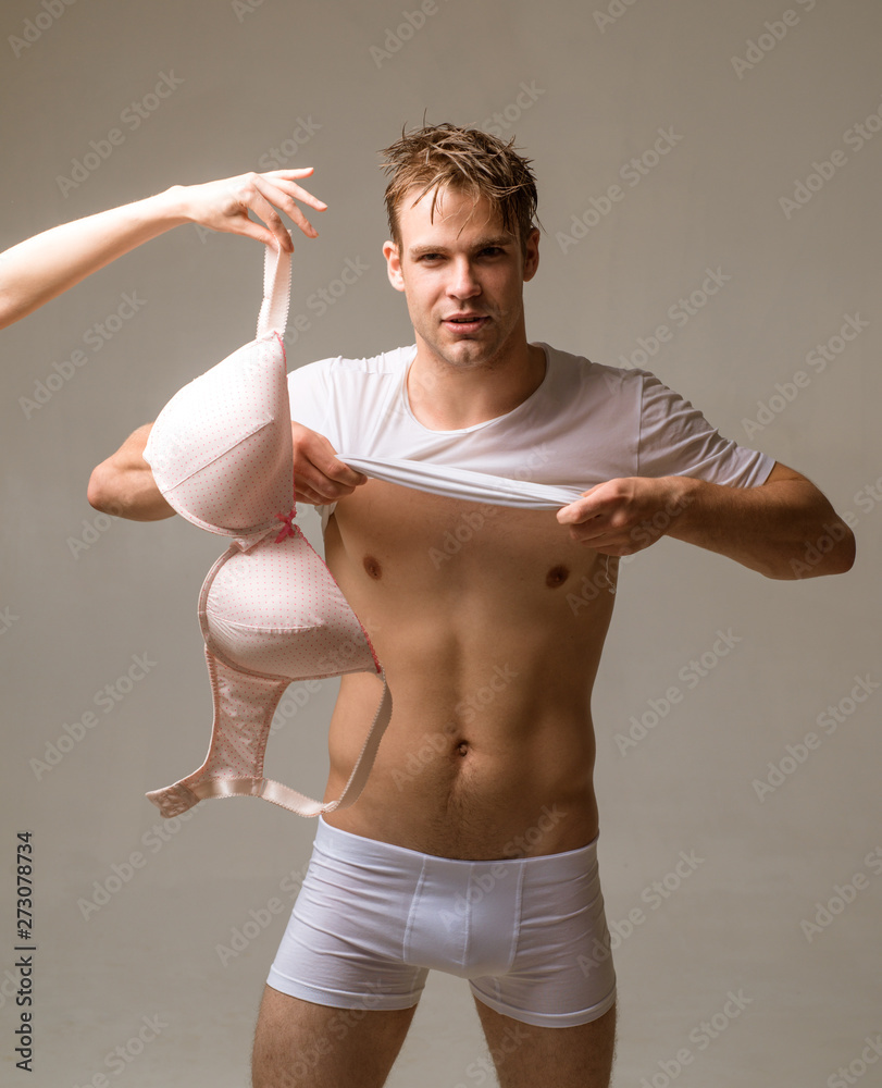 Muscle sexy young naked boy takes off clothes before intimate moment,  looking on the bra. Stock Photo | Adobe Stock