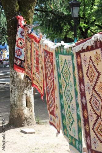 Hand-made carpets hanging in street market. © annakonchits