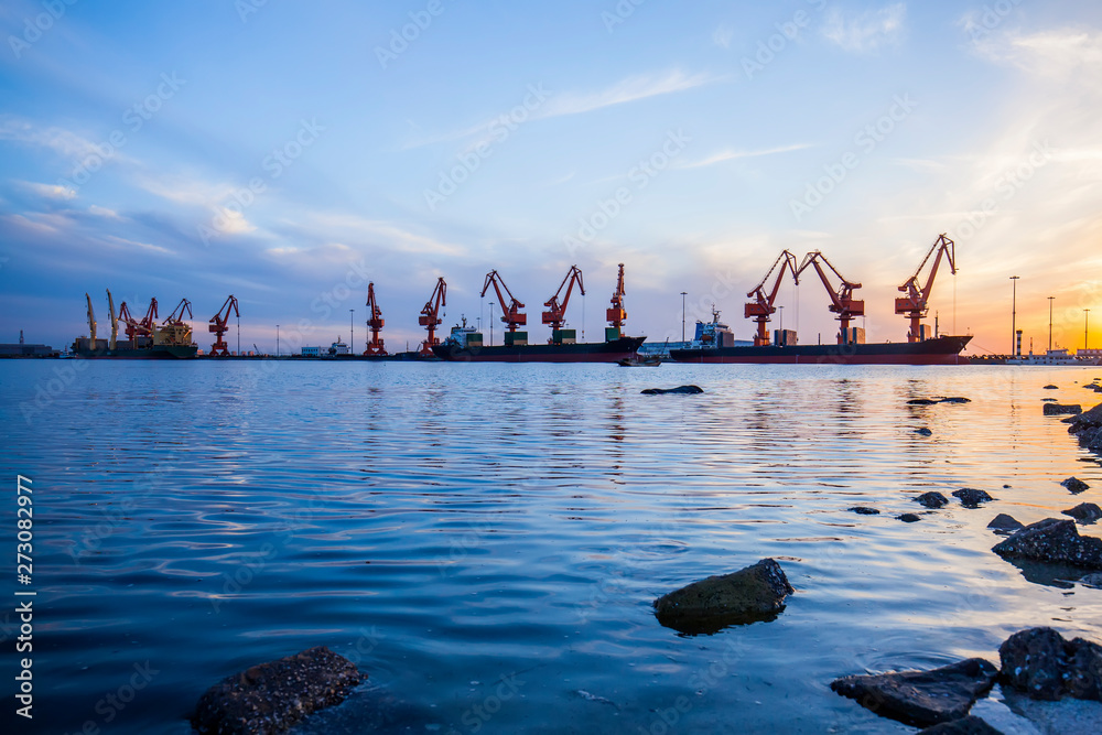 Fototapeta premium Gantry crane and cargo ship in the evening