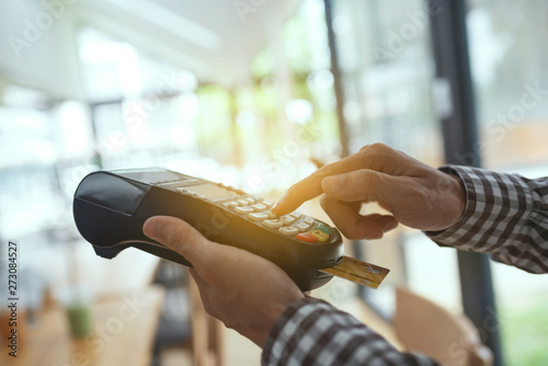 Young man using payment terminal machine.