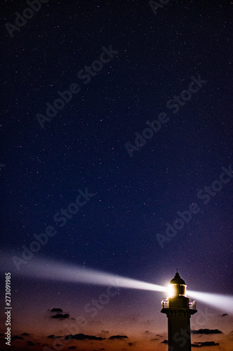 lighthouse at night with moon and stars