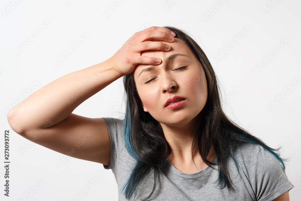 Obraz premium young girl grabs her head with her hand and depicts a severe headache. On white background