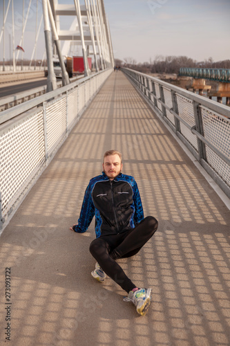 one young man, athlete and runner or jogger, sitting on a ground on a bridge.