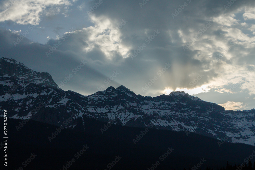 Sun breaking through clouds over mountain range