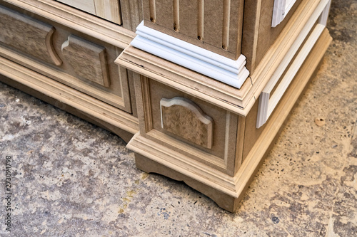 Mdf cabinet carcass with moldings and wooden carved capital. Wooden furniture manufacturing process