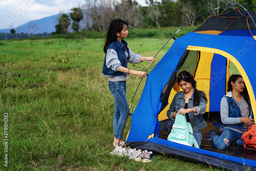 Friends Camping concept.Young women  in casual wear and enjoy  camping at forest.Girls are helping to spread the tent for sleeping in the forest at night.
