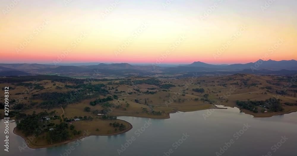 Rising aerial view of brown hills and mountains surrounding lake Moogera at sunset - Queensland, Australia. Golden, pink horizon. Rising aerial view of brown hills and mountains surrounding lake Moogera at sunset - Queensland, Australia. Golden, pink horizon.