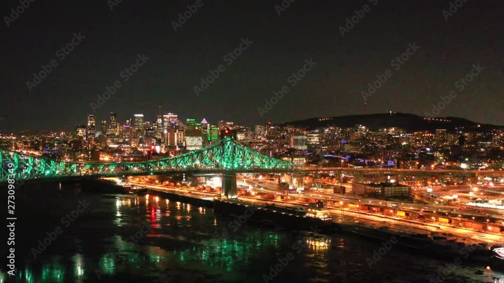 Drone flies around a large bridge at night in the winter with colorful lights in the city. Drone flies around a large bridge at night in the winter with colorful lights in the city.