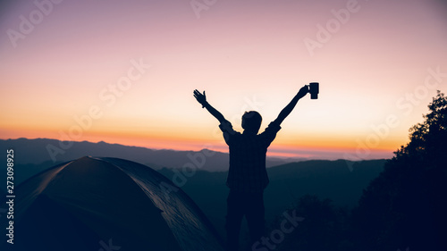 freedom time of hiker man holding coffee cup near camping tent on mountains at sunset background. travel concept.