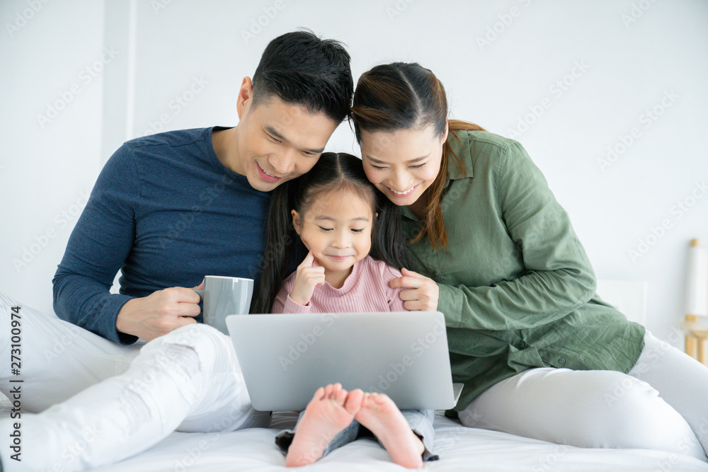 Parents having fun with their little daughter on bed with tablet. Family spending time at the holiday , happy family concept. Parents having fun with their little daughter on bed with tablet. Family spending time at the holiday , happy family concept.