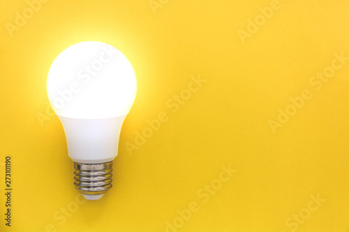 LED light bulb on yellow background, concept of ideas, creativity, innovation or saving energy, copy space, top view, flat lay