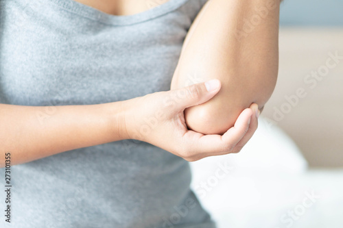 Closeup woman hand holding elbow with pain lying on bed, health care and medical concept