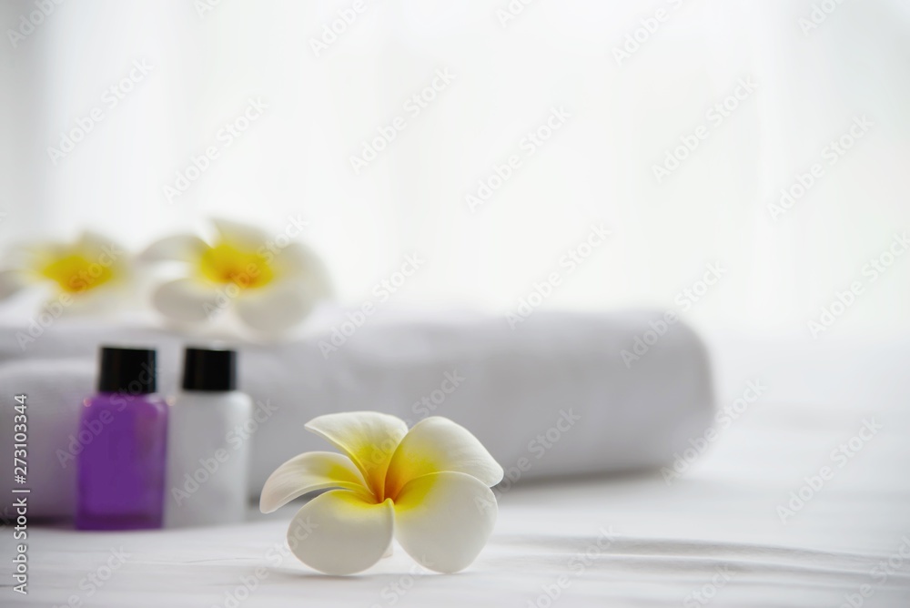 Hotel towel and shampoo and soap bath bottle set on white bed with plumeria flower decorated - relax vacation at the hotel resort concept Hotel towel and shampoo and soap bath bottle set on white bed with plumeria flower decorated - relax vacation at the hotel resort concept