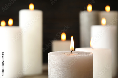 Alight wax candle on blurred background, closeup. Space for text