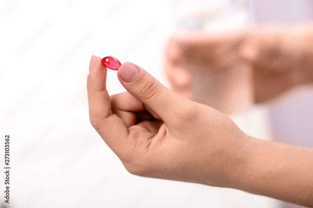 Woman holding pill and glass of water on blurred background, closeup. Space for text Woman holding pill and glass of water on blurred background, closeup. Space for text